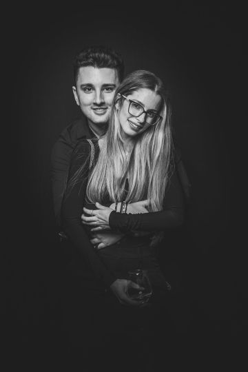 Retrato editorial de una pareja abrazada con fondo negro