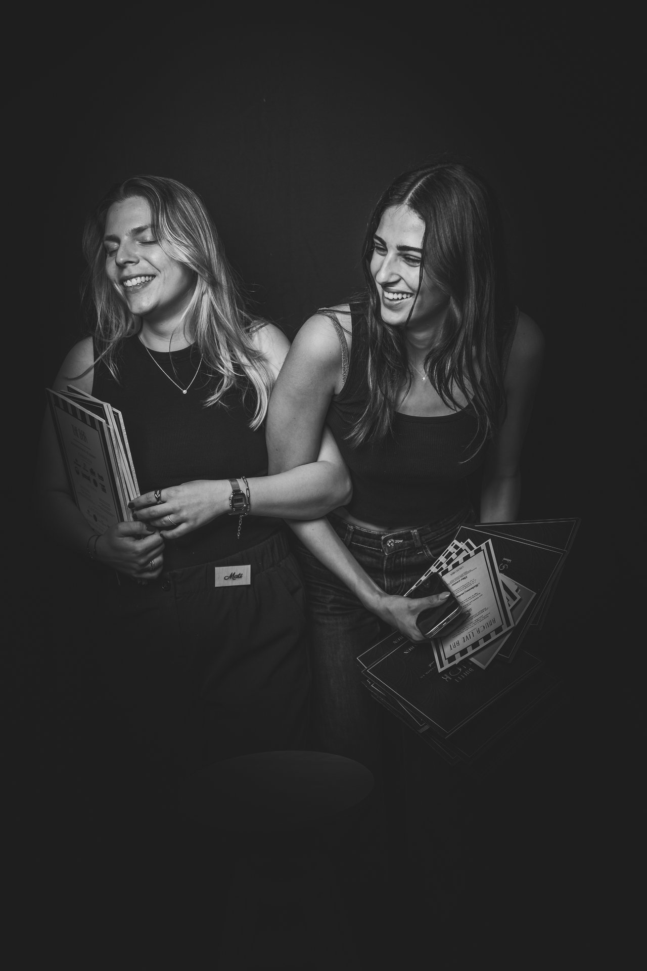 Retrato de dos amigas riendo con fondo negro